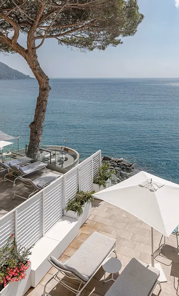Ambientazione outdoor con pannelli frangivista Modularte bianchi su misura, fioriere integrate e arredo giardino in una location vista mare.