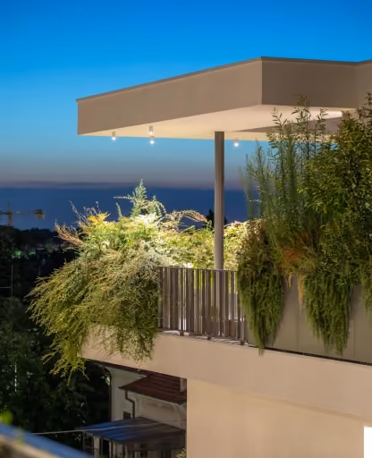Illuminazione notturna per giardini pensili Modularte con fioriere integrate e piante a cascata su un terrazzo moderno con vista.